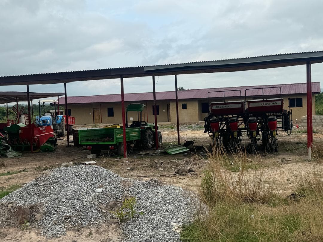 Aframso farm compound machinery shed housing tractors, dump trailers, and Baldan precision planter, with compound buildings behind
